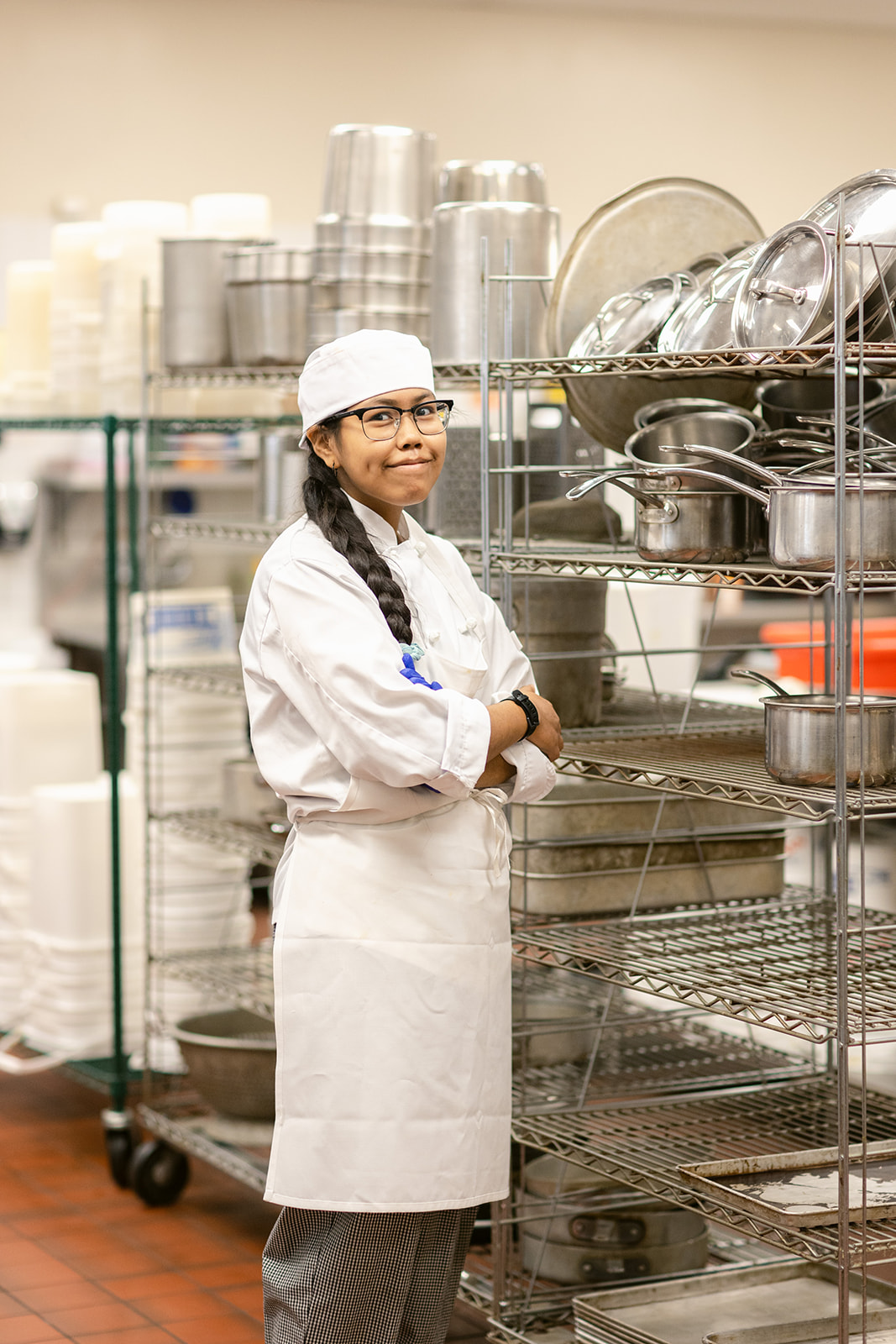 A woman in cooking attire standing in a kitchen.